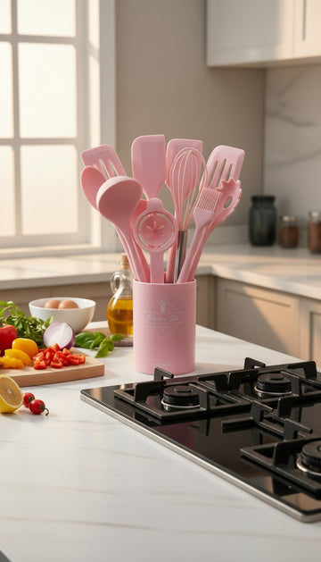 Pink kitchen utensil set in a holder on a kitchen counter with vegetables and a stove.
