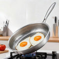 Tidings & Twinkle ForgeCore titanium frying pan with hammered non-stick surface cooking two fried eggs.