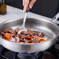 Tidings & Twinkle ForgeCore titanium frying pan with hammered non-stick surface cooking beef and vegetables.
