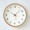 Tidings & Twinkle minimalist 10-inch round wooden wall clock with a white face and black Arabic numerals.